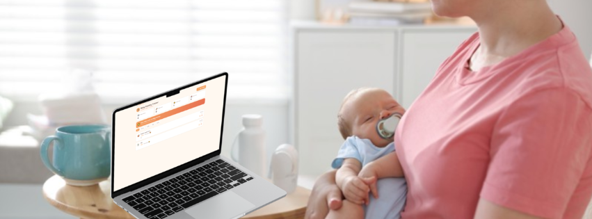 Woman holding a baby and using a laptop in a home office setting