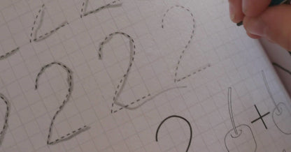 A little girl is tracing numbers