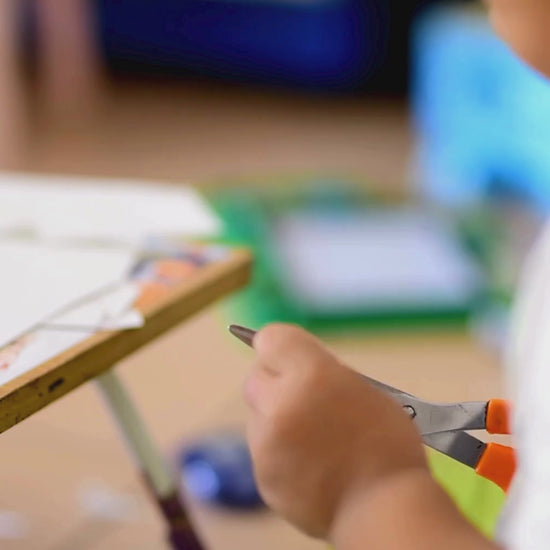 A child carefully cutting out shapes and pieces on the cut-out pages of KidzzyLab busy book