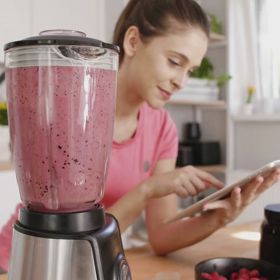 A mother using the ebook on a tablet while preparing baby food in the kitchen.